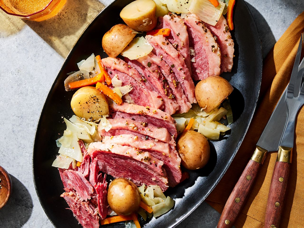 Slowcooked corned beef served with cabbage carrots and potatoes on a black plate