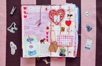 Open scrapbook with heart-themed decorations and handwritten notes about romance, surrounded by small craft items and stickers