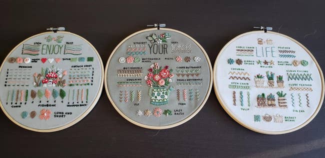 Three embroidery hoops with detailed floral and text patterns display various stitches like French knot, lazy daisy, and zig zag