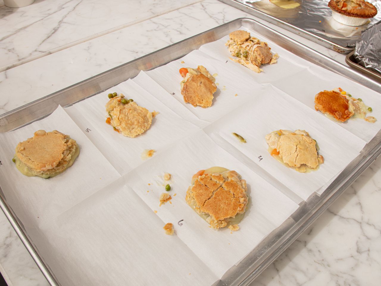 A tray with several portions of baked goods placed on parchment paper some appear to be incomplete or bitten