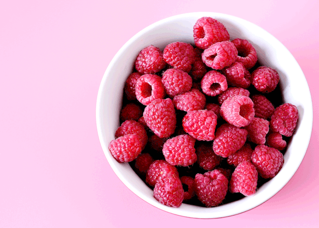 high fiber fruit: bowl of raspberries on pink background