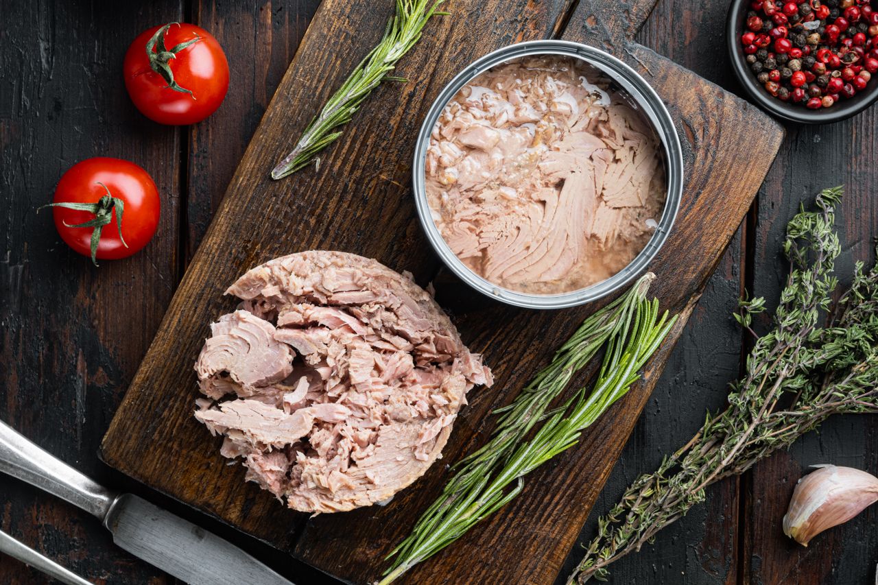 Canned tuna on a dark wooden cutting board