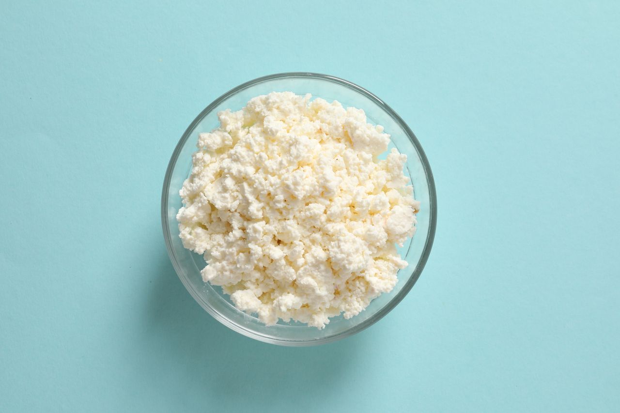 Glass bowl of cottage cheese of a light blue backdrop