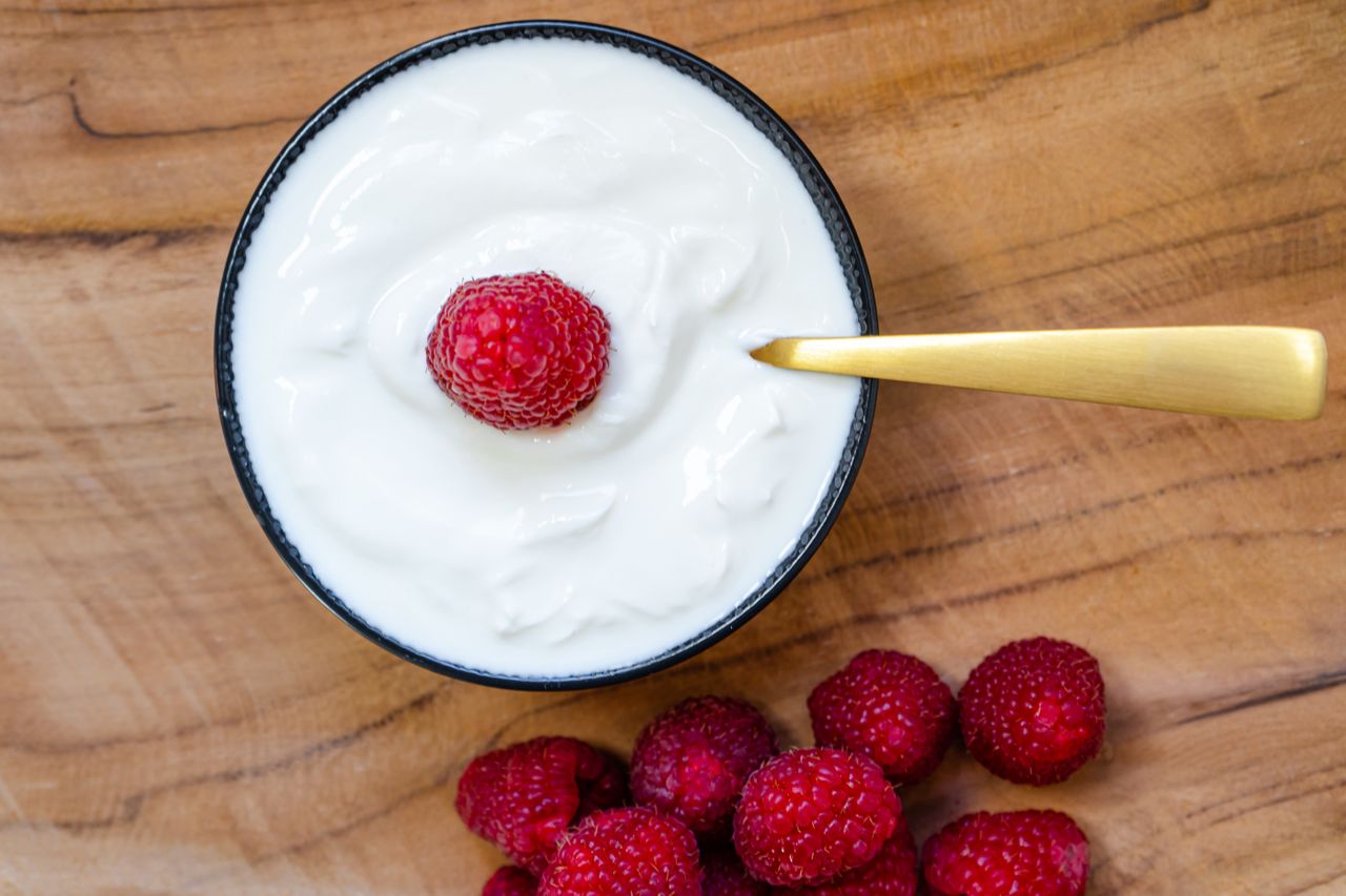 bowl of yogurt topped with fresh raspeberries