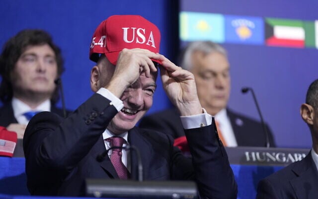 Giovanni Vincenzo Infantino, president of FIFA, tries out a USA hat during a Board of Peace meeting at the US Institute of Peace, Thursday, Feb. 19, 2026, in Washington. (AP Photo/Mark Schiefelbein)