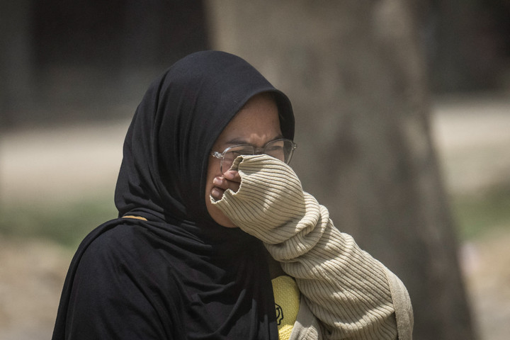 Warga Aceh Tamiang berjalan dengan masker untuk melindungi diri dari debu pascabanjir.