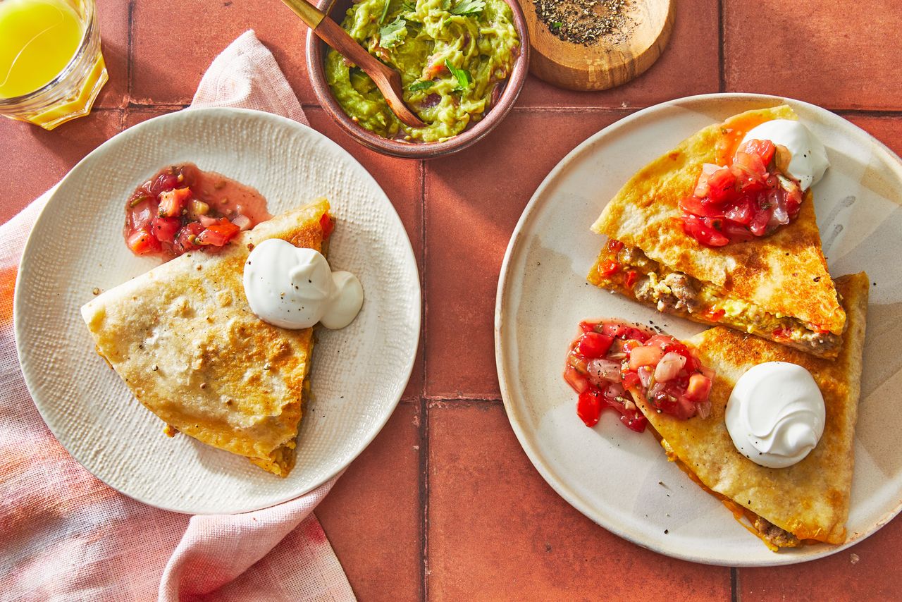 Southern Living Breakfast Quesadilla cut into wedges on plates topped with salsa and sour cream