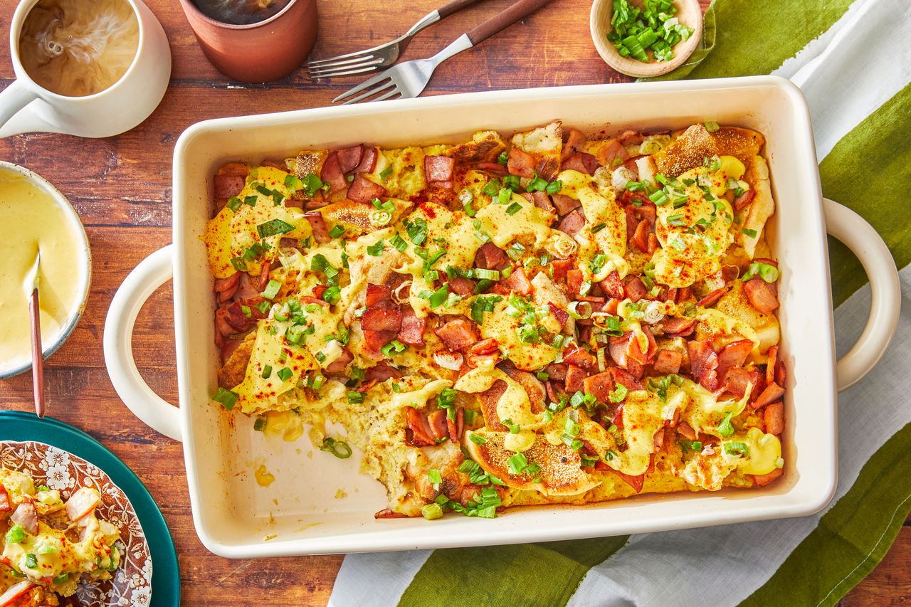 Southern Living Eggs Benedict Casserole on a table to serve with a serving on a plate beside it