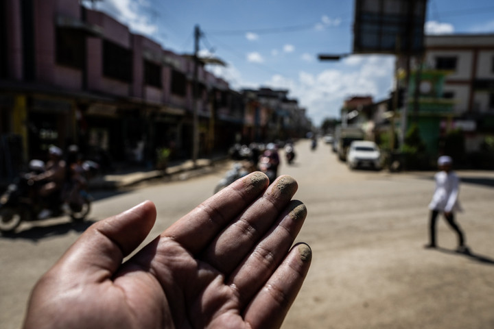Warga berjalan di dekat kelambu yang terpasang di sebuah tempat makan, sebagai upaya pencegahan debu.