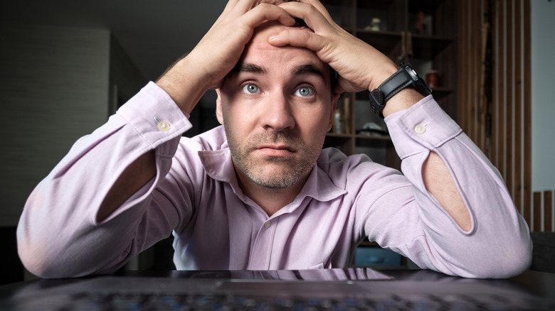 A man looks at his computer screen in frustration.