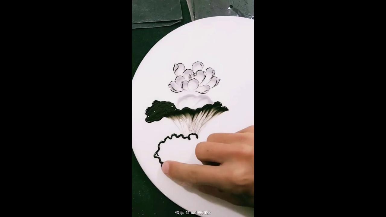 The art of painting black ink lotus flowers on white porcelain plate
