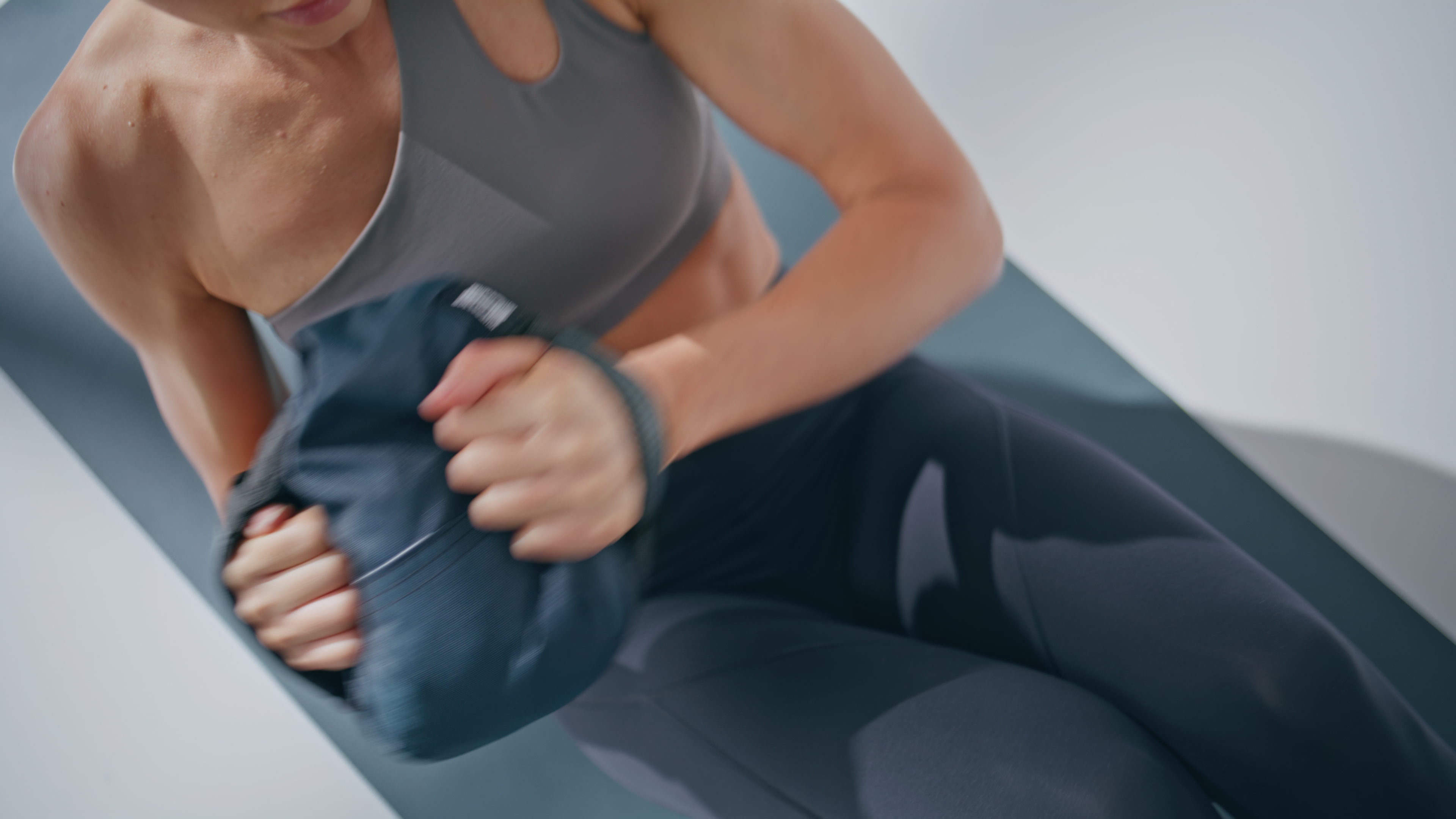 Person in athletic wear exercising with a weight on a mat