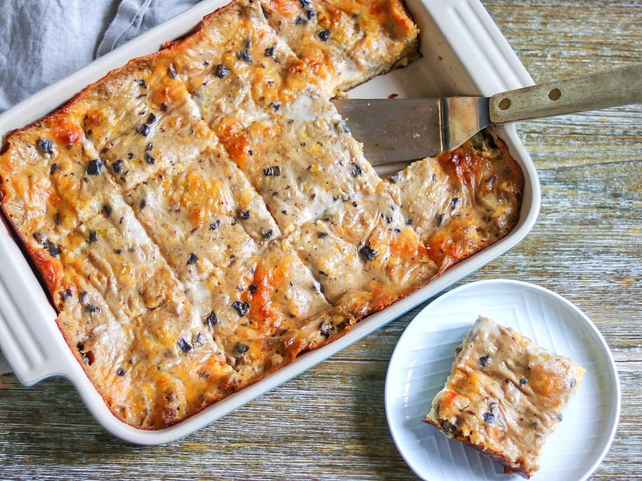 Breakfast sausage casserole in casserole dish and one slice on white plate
