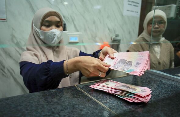 A currency exchange officer counting Rupiah banknotes at a money exchange office in India