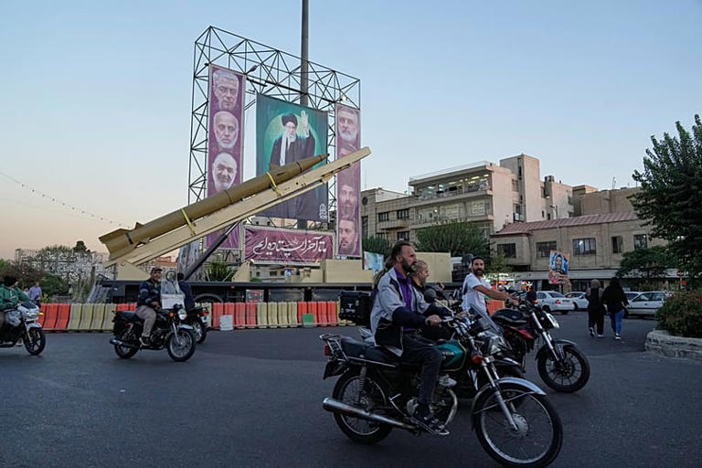 أشخاص على دراجات نارية يمرون أمام صاروخ محلي الصنع في ساحة بهارستان بطهران، يوم الخميس 25 سبتمبر/أيلول 2025. Vahid Salemi/Copyright 2025 The AP. All rights reserved