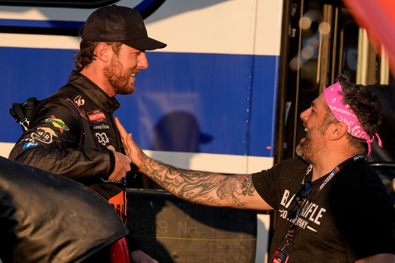 NASCAR Truck driver Garrett Mitchell, better known as "Cleetus McFarland, left, speaks to crew in the garage area during a practice at Daytona International Speedway, Thursday, Feb. 12, 2026, in Daytona Beach, Fla. (AP Photo/Mike Stewart)