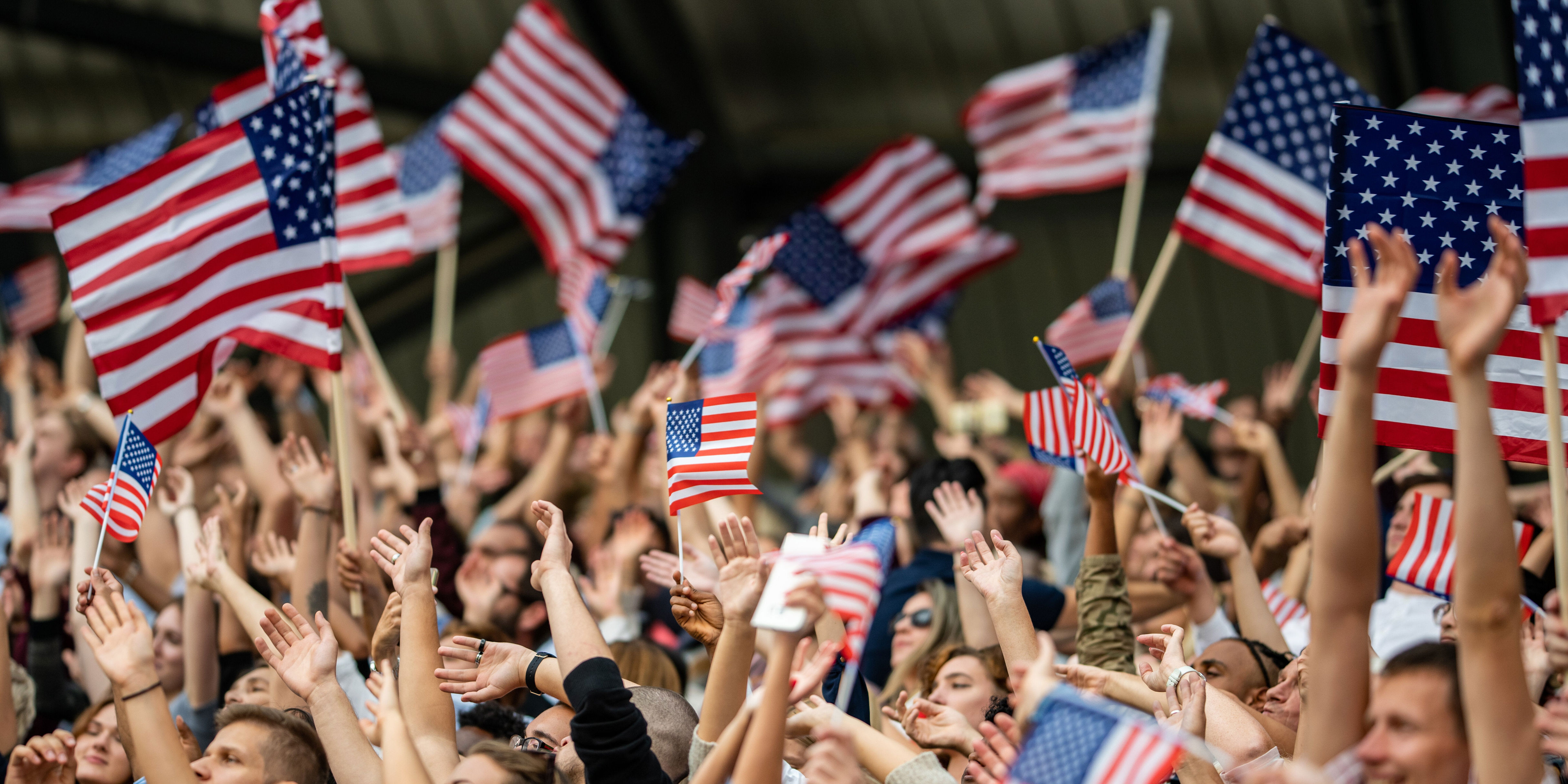 Large crowd of people at the Olympics cheering for USA and waving American flags. (Photo: vm via Getty Images)