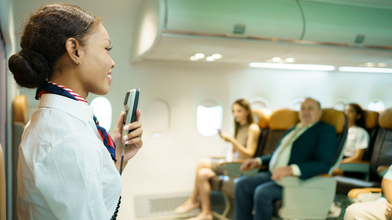 Flight attendant speaking to passengers on a plane