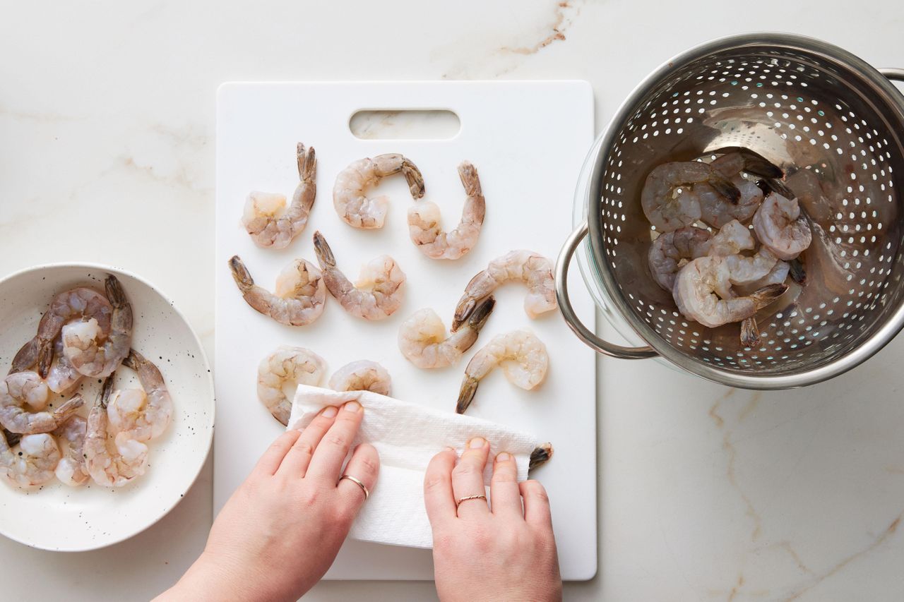 Drying shrimp on cutting board with paper towel