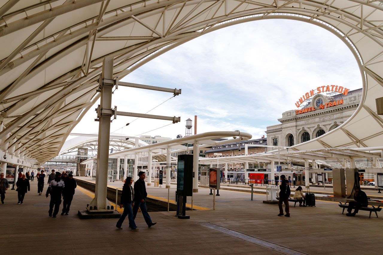 Train platforms at Denver Union Station people walking under modern canopy and the station building visible in the background