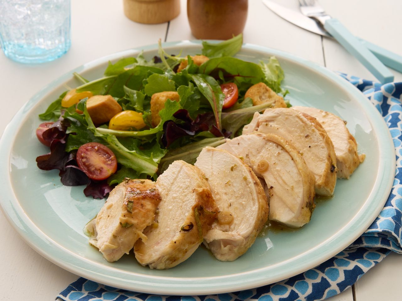A plate of sliced baked beer can chicken served with a simple salad