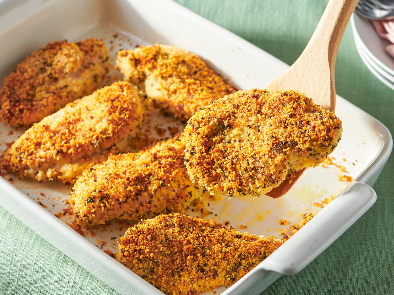 Baked parmesan-crusted chicken served in a white casserole dish.