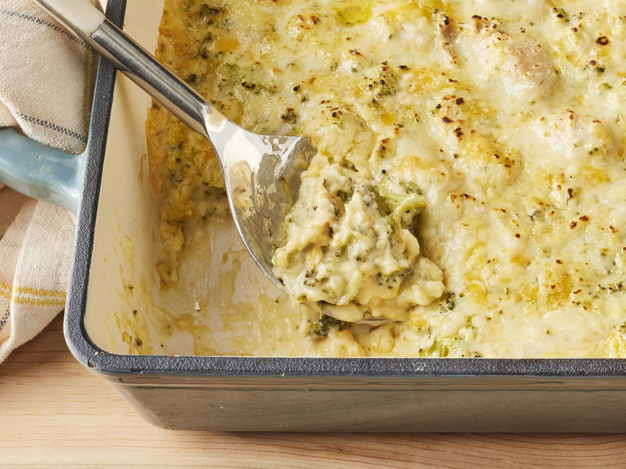 high angle looking down at a casserole dish of cheesy chicken and broccoli casserole with a spoonful resting in the dish
