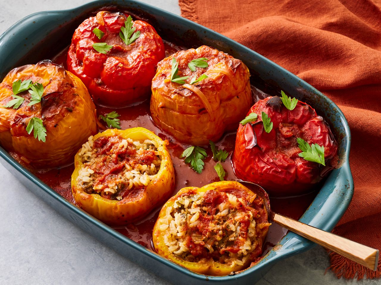 A baking dish with beef and rice stuffed bell peppers, garnished with chopped parsley
