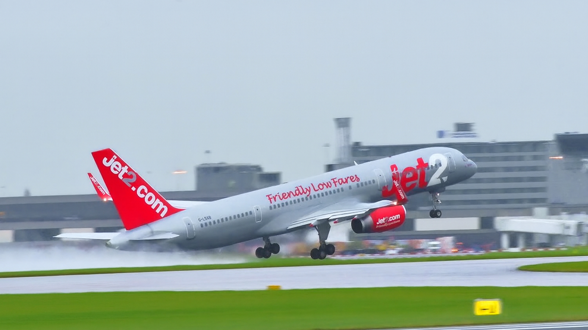 Passenger jet accelerates hard on rain-soaked runway