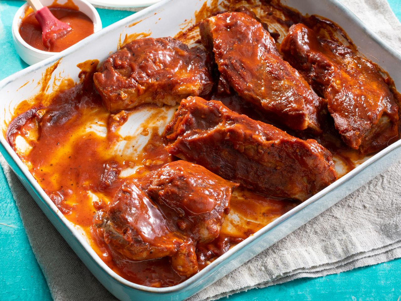high angle view of saucy BBQ ribs served in a white baking dish
