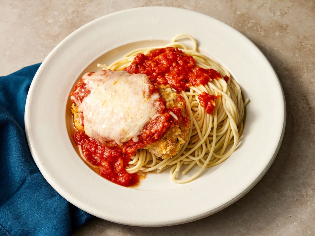 looking down at a plate of baked chicken parmesan over pasta