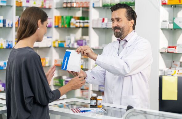 Smiling male pharmacist giving medicine to customer