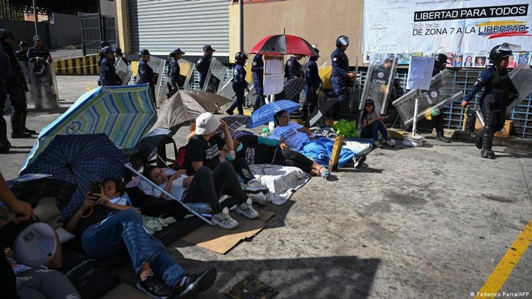 Familiares de presos políticos yacen en el suelo frente a agentes de policía durante una protesta frente a una cárcel en Caracas (14.02.2026)