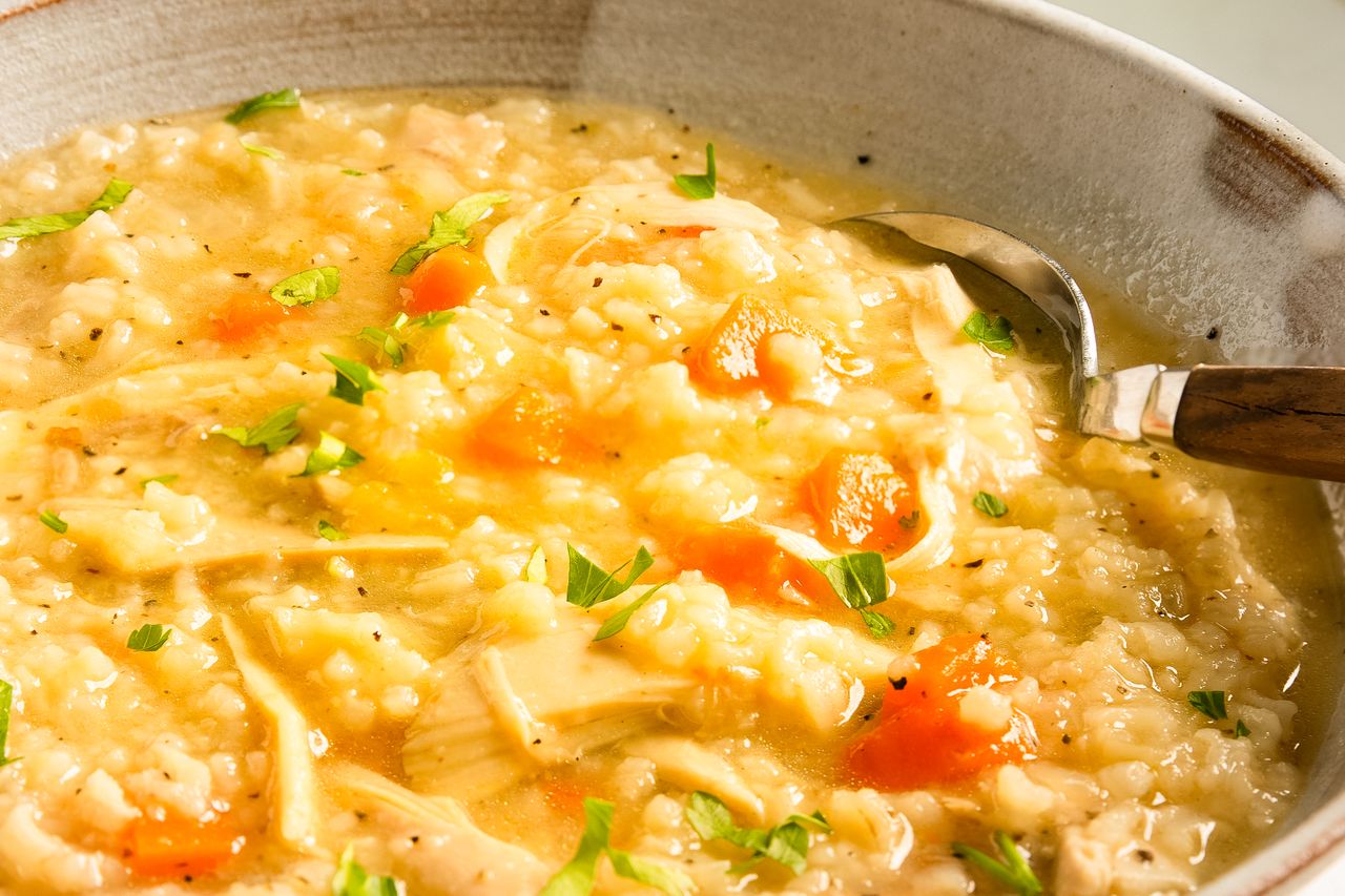 A bowl of chicken and rice soup with a spoon