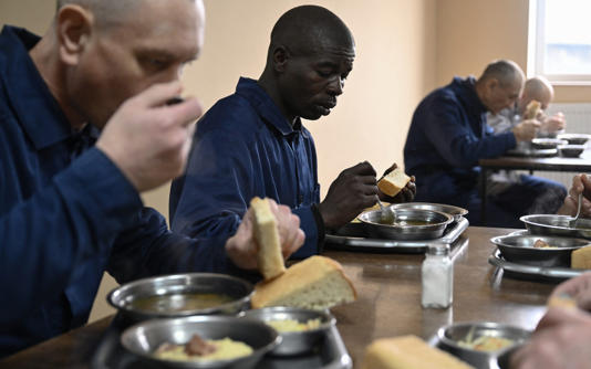 Evans Kibet, centre, a Kenyan citizen, eats his lunch at a detention centre for prisoners of war after being captured by Ukraine - Genya Savilov/AFP via Getty Images