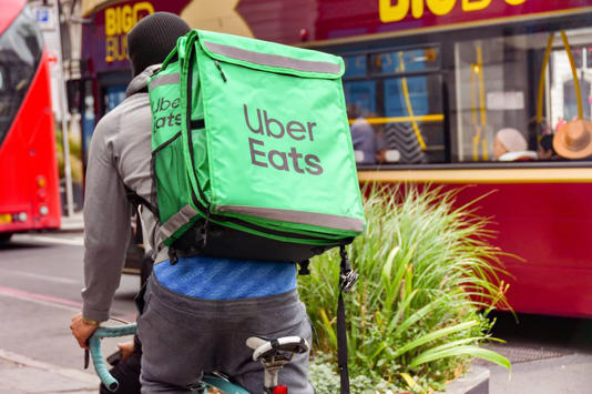 London, England, UK - 28 June 2023: Cyclist carrying an insulated delivery container for the Uber Eats food delivery business cycling on a street in central London.