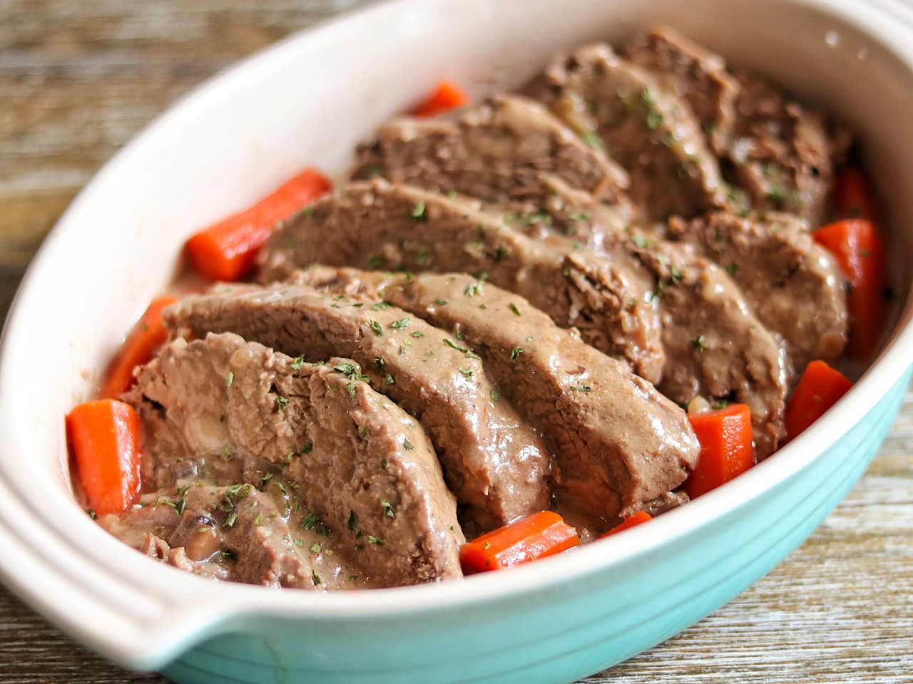 Sliced pot roast in casserole dish with carrots