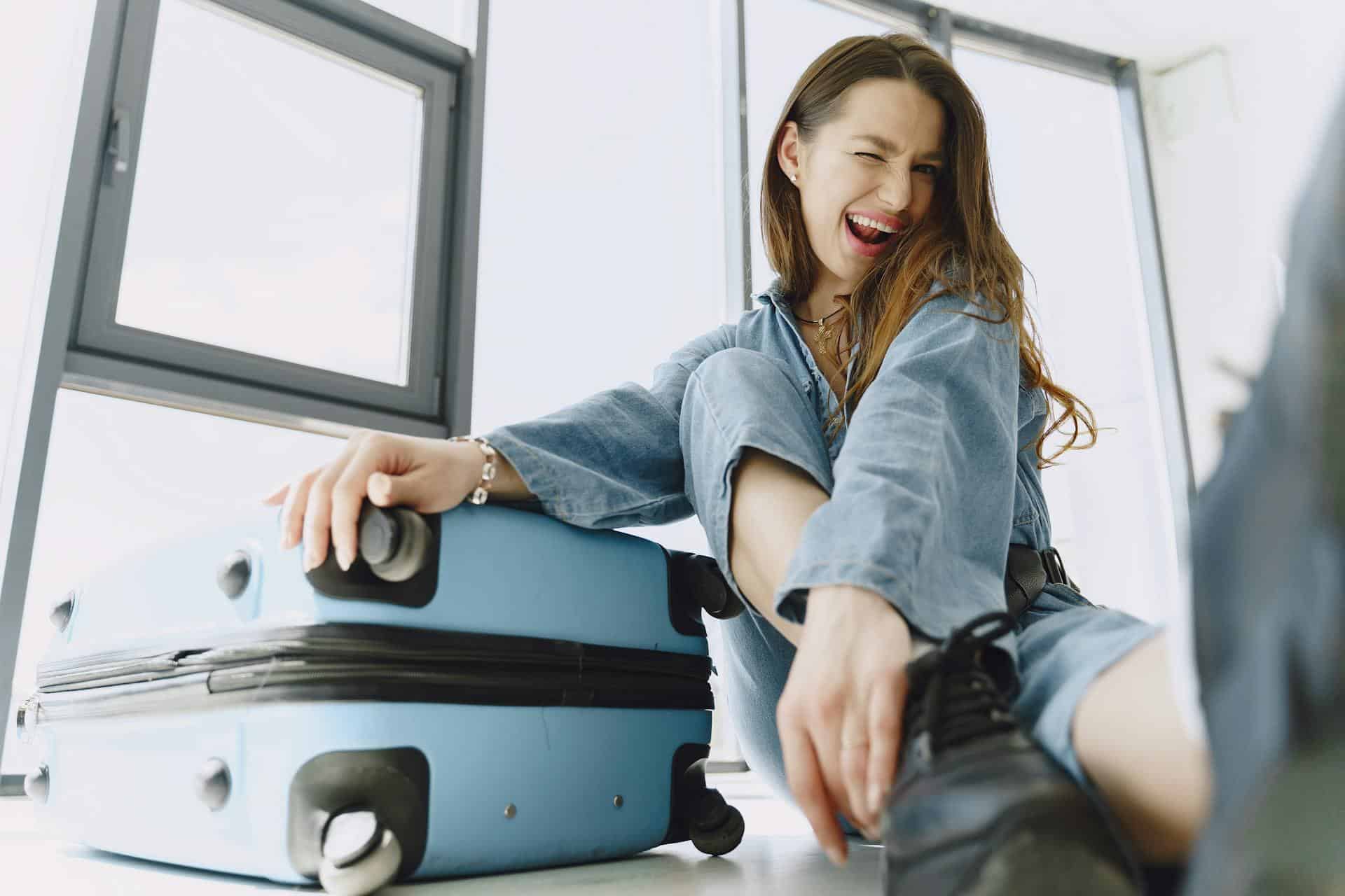 Young woman winking at camera with luggage next to her