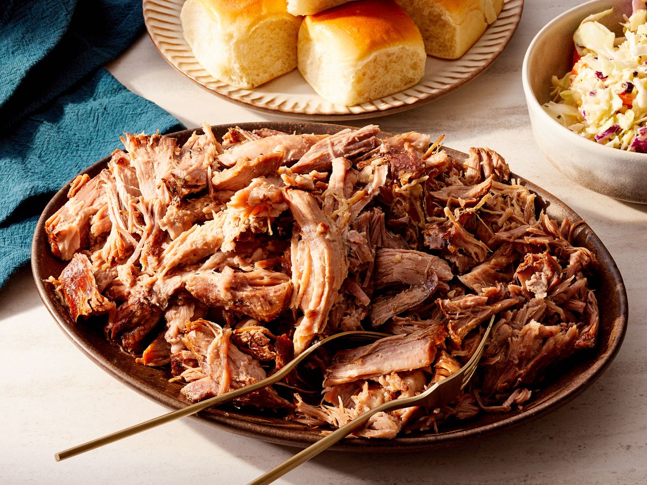 A platter of shredded Kalua pork served with buns and coleslaw on the side
