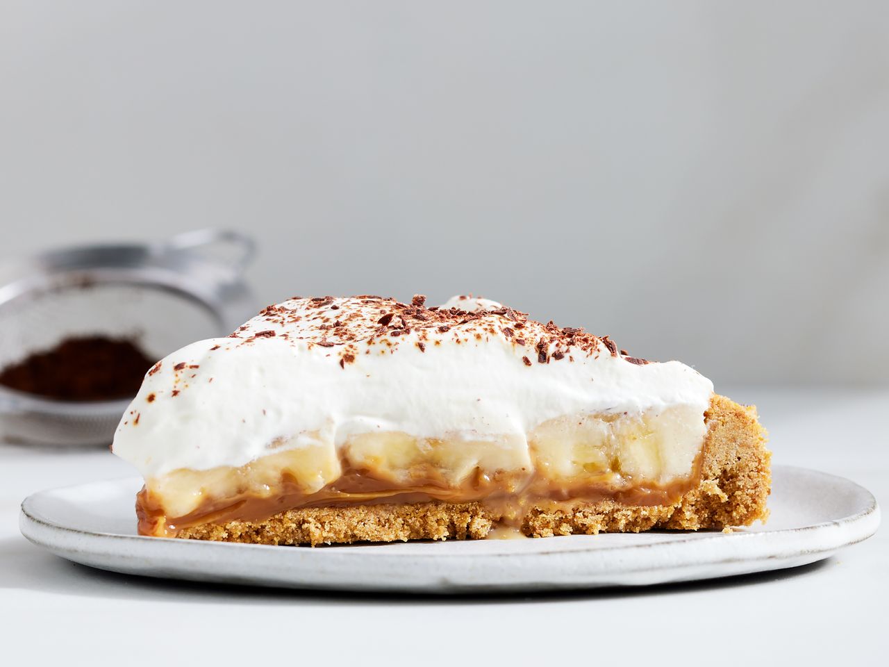 a low angle view looking at a single, plated slice of banoffee pie.