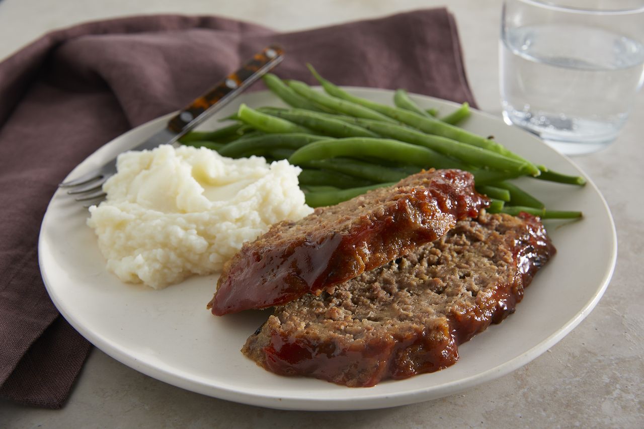 low angle looking into a plate of sliced meatloaf served with green beans and mashed potatoes