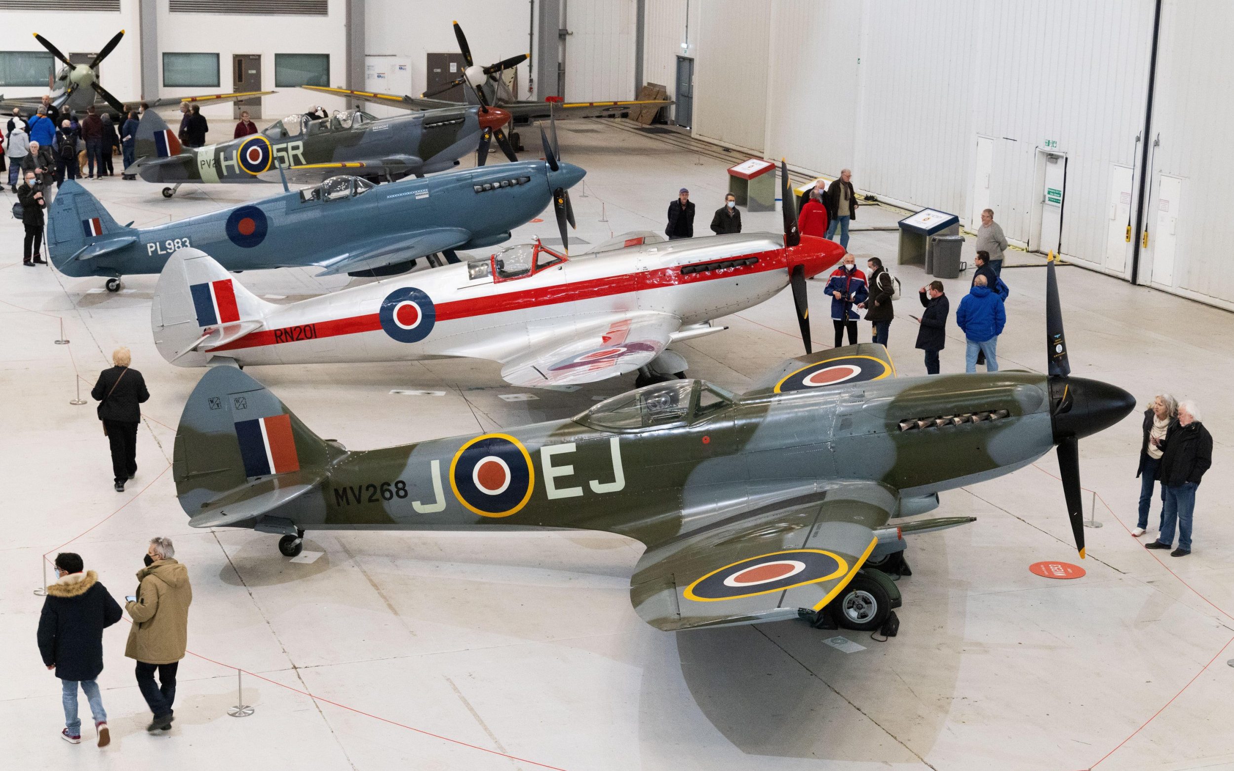 People looking at spitfire fighter planes inside a Hangar at Duxford Air Museum