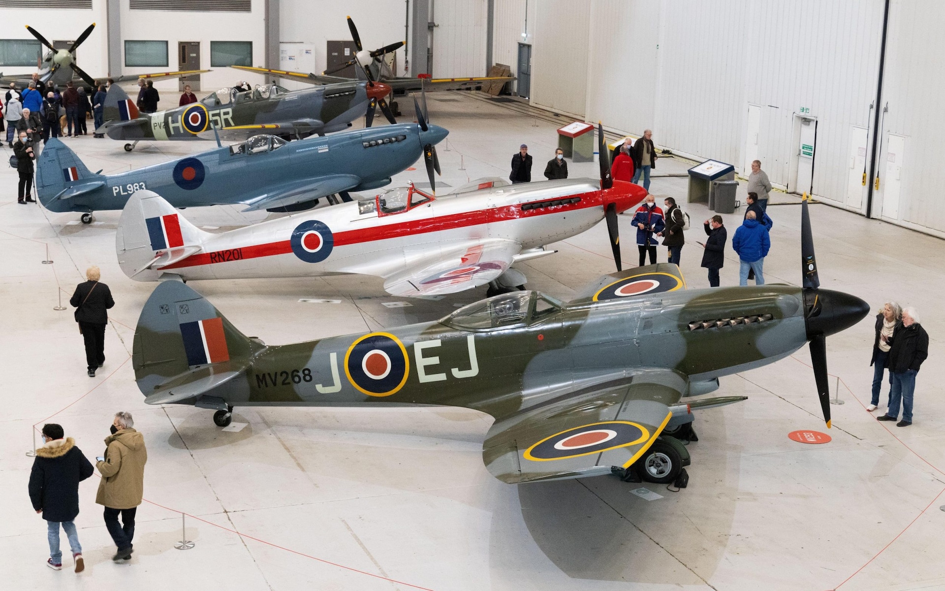 People looking at spitfire fighter planes inside a Hangar at Duxford Air Museum