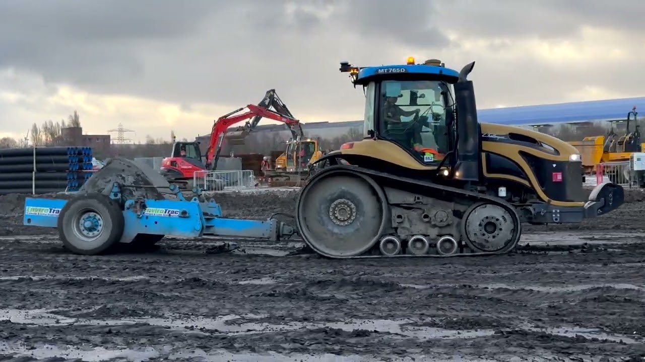 Powerful tractor compacting muddy construction site