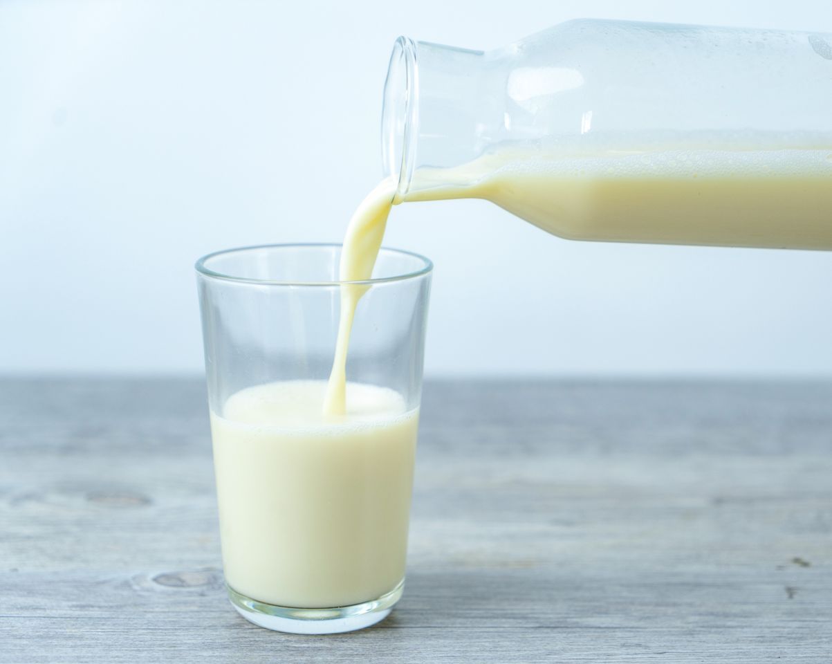 Pouring milk in drinking glass.