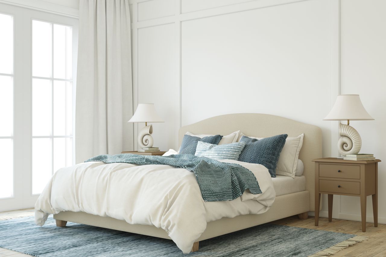 A neatly made bed with pillows two nightstands and decorative lamps in a brightly lit bedroom