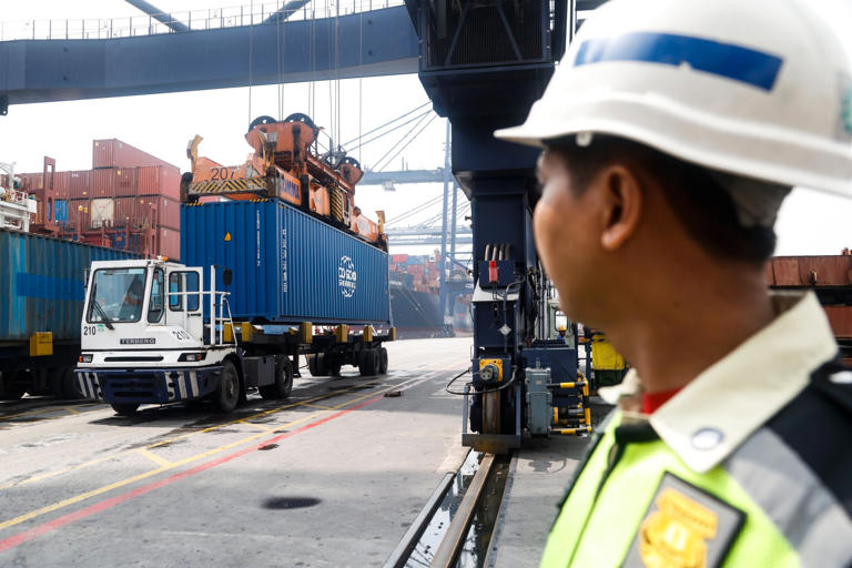 A worker looks on as shipping containers are loaded onto trucks at the Jakarta International Container Terminal in Indonesia. Photo: EPA