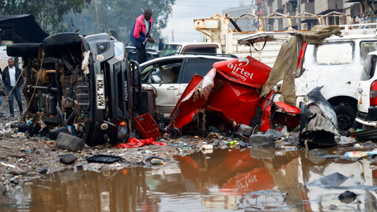 A man looks through the wreckage of private vehicles destroyed following heavy rainfall in the Grogan area of Nairobi