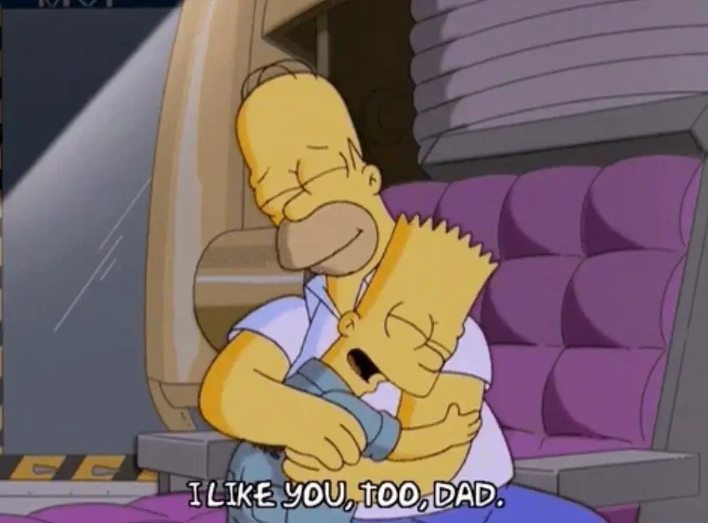 Homer and Bart Simpson sitting and hugging on a couch. Bart says,