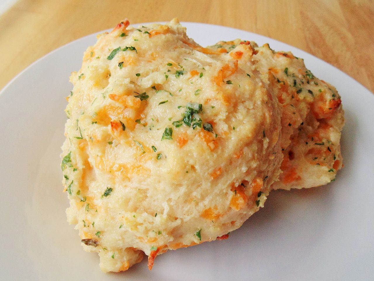 a close up view of two cheddar bay biscuits on a white plate.